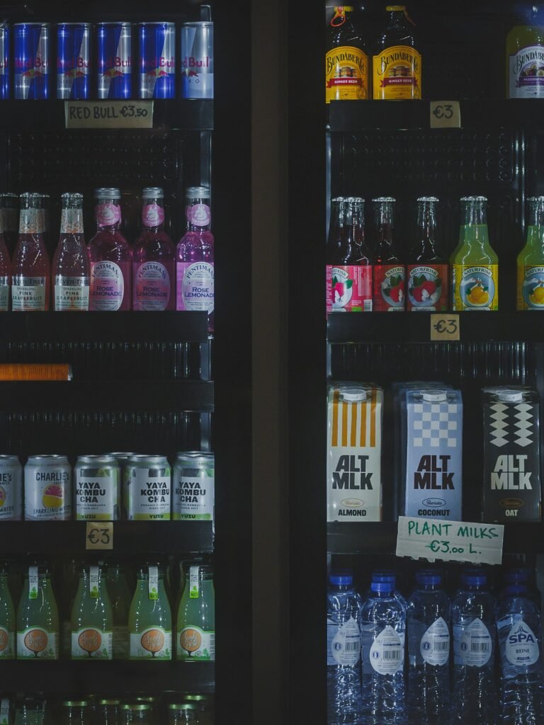 Refrigerated convenience-store cooler filled with assorted canned and bottled beverages