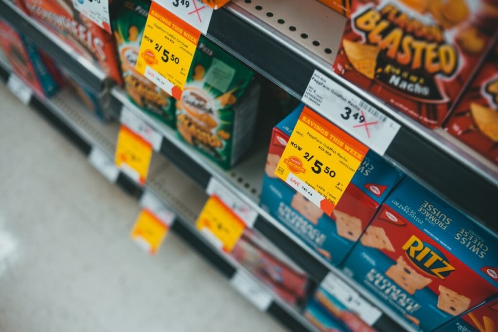 Store shelves stocked with packaged snacks and price labels on the shelf edge